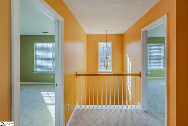 hallway with carpet, baseboards, and a textured ceiling