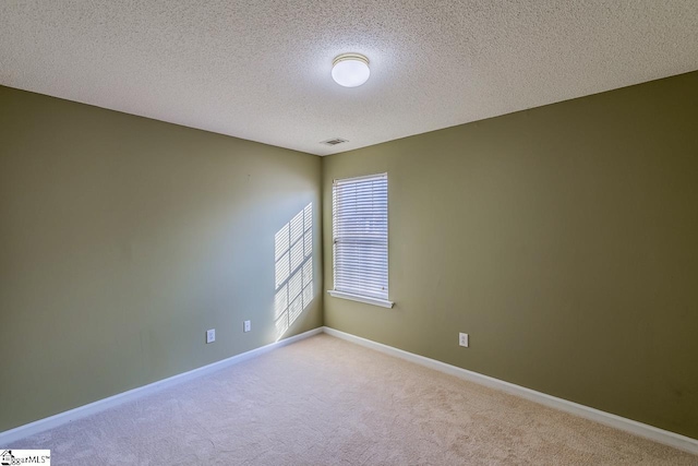 spare room with a textured ceiling, baseboards, visible vents, and light carpet