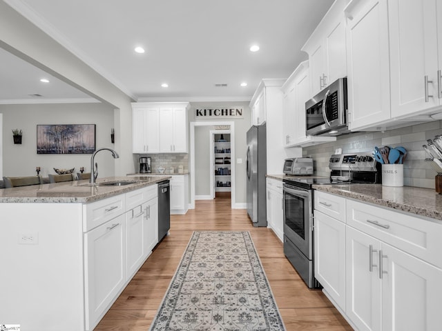 kitchen featuring ornamental molding, light wood-style flooring, white cabinets, stainless steel appliances, and a sink