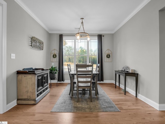 dining room with light wood-type flooring, baseboards, and crown molding