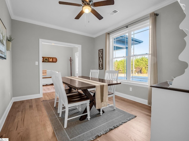 dining space featuring light wood finished floors, visible vents, ceiling fan, and ornamental molding