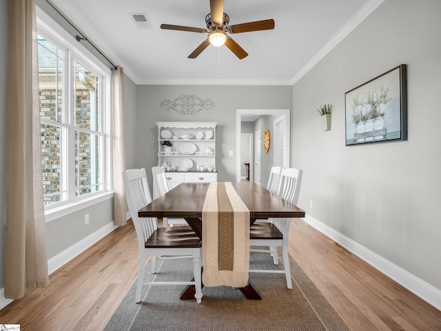 dining room with visible vents, light wood-style flooring, baseboards, and ornamental molding