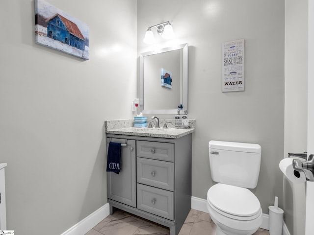 bathroom featuring vanity, toilet, baseboards, and marble finish floor