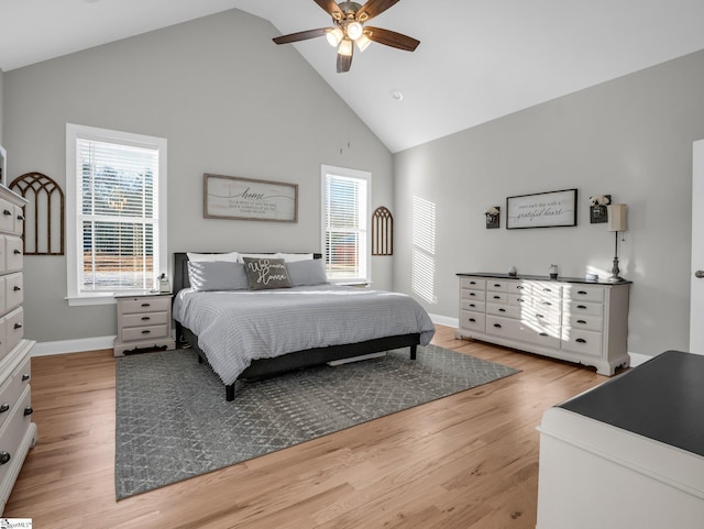 bedroom featuring light wood finished floors, baseboards, high vaulted ceiling, and ceiling fan