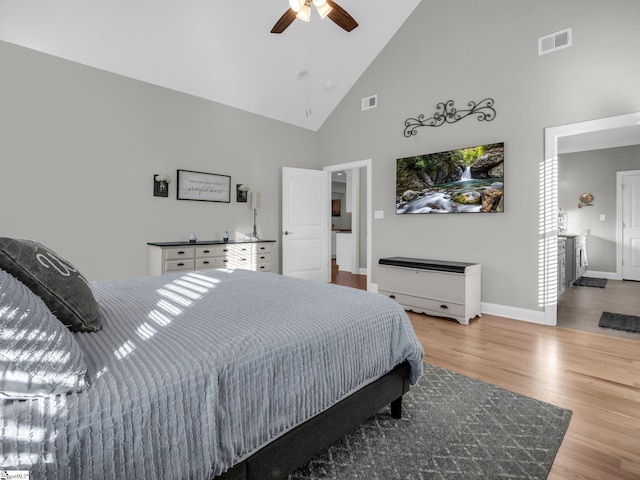 bedroom featuring visible vents, baseboards, wood finished floors, high vaulted ceiling, and a ceiling fan