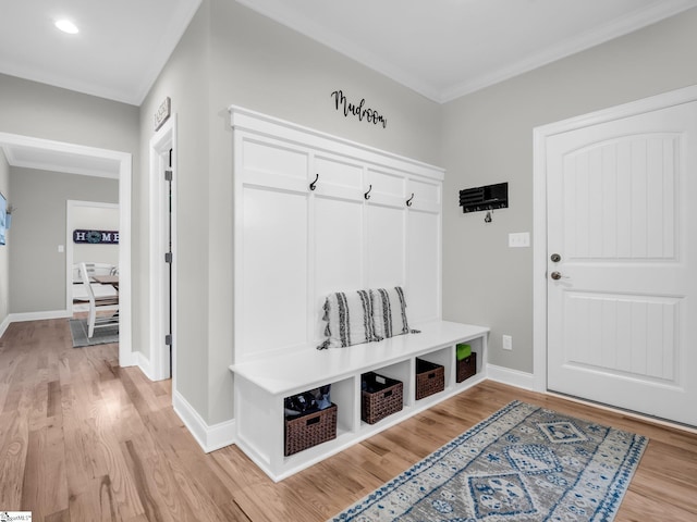 mudroom with crown molding, light wood-style flooring, and baseboards