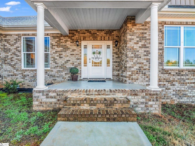 entrance to property featuring brick siding and a porch