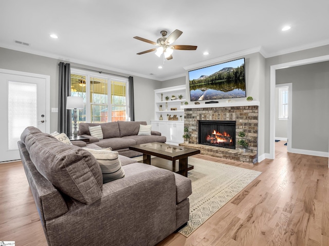 living room featuring a ceiling fan, crown molding, a fireplace, and visible vents