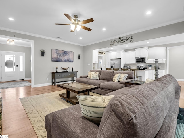 living area with recessed lighting, light wood-style floors, crown molding, baseboards, and ceiling fan