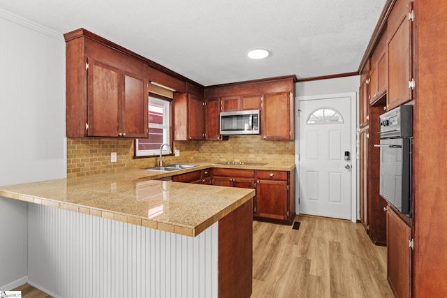 kitchen with a sink, stainless steel microwave, wall oven, a peninsula, and black electric stovetop