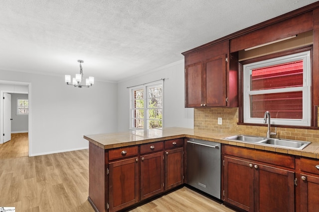 kitchen featuring a sink, stainless steel dishwasher, a peninsula, an inviting chandelier, and light wood finished floors