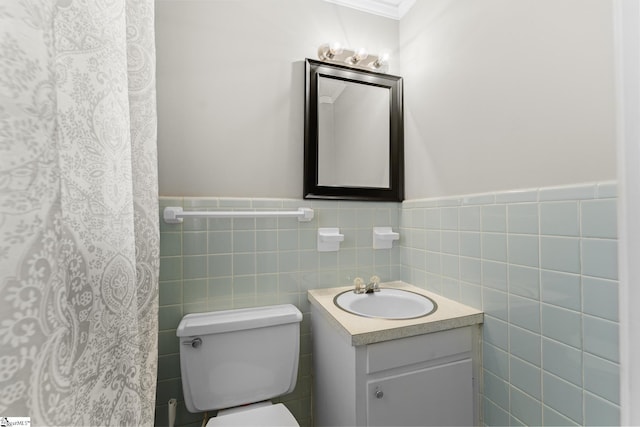 bathroom with a wainscoted wall, toilet, tile walls, and vanity