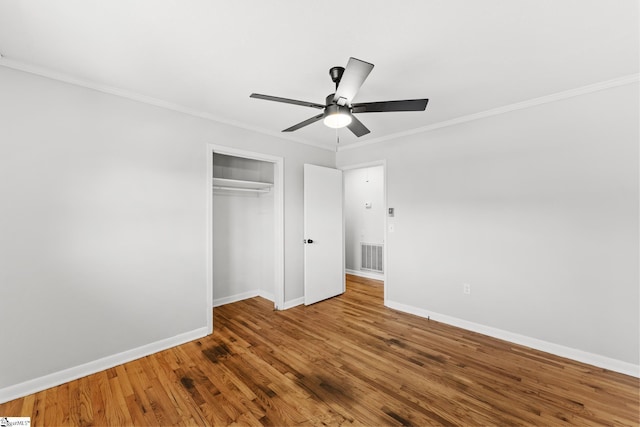 unfurnished bedroom featuring baseboards, wood finished floors, a closet, and ornamental molding