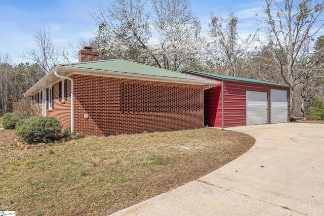 view of home's exterior with concrete driveway, a yard, metal roof, and a chimney