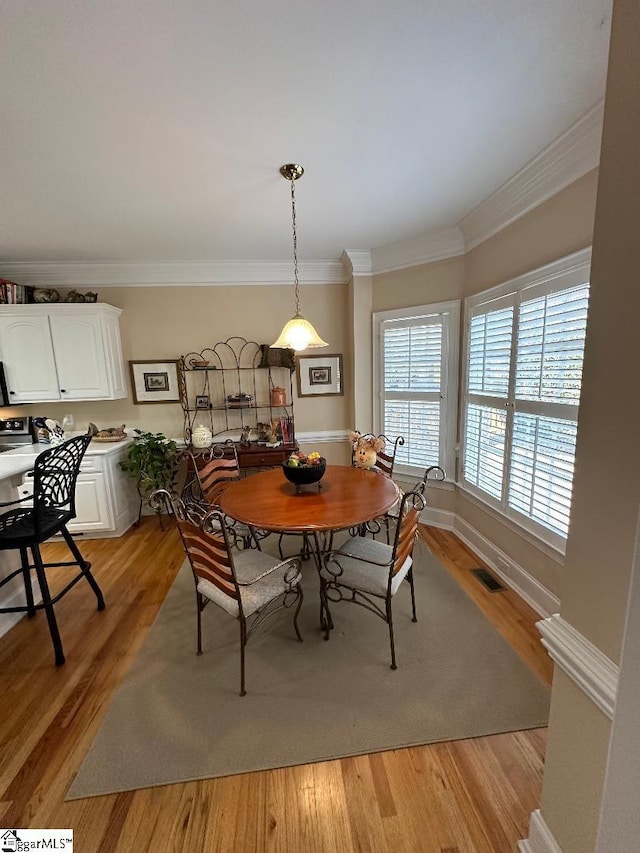 dining space featuring crown molding, baseboards, visible vents, and light wood finished floors