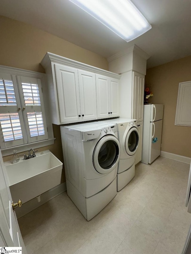 laundry room with baseboards, cabinet space, and separate washer and dryer