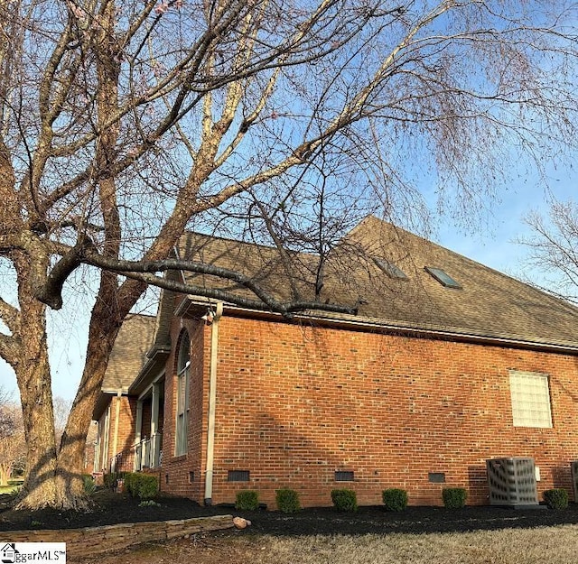 view of side of home featuring brick siding, roof with shingles, and crawl space