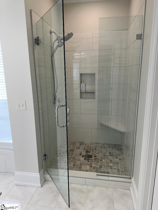 bathroom with baseboards, a shower stall, and tile patterned flooring