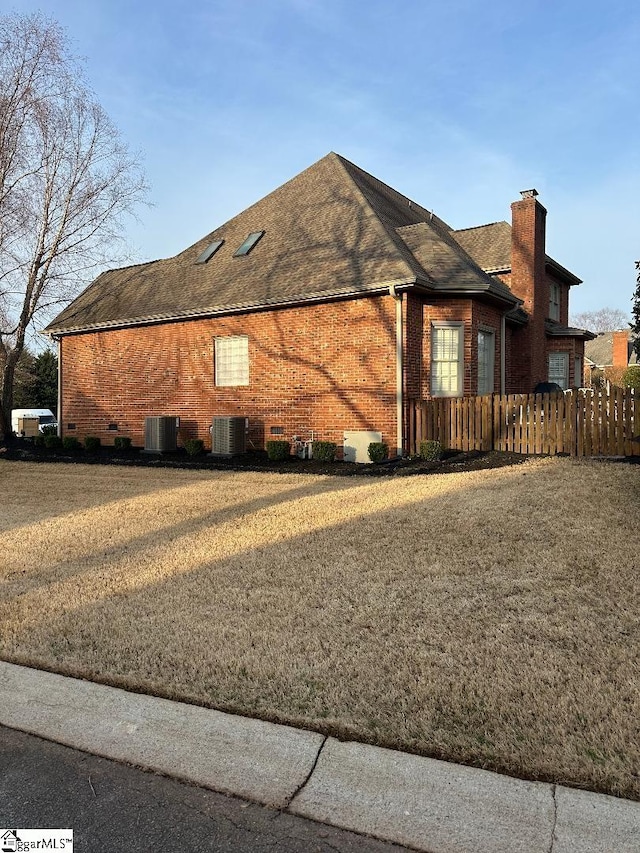 view of home's exterior with cooling unit, a lawn, and brick siding