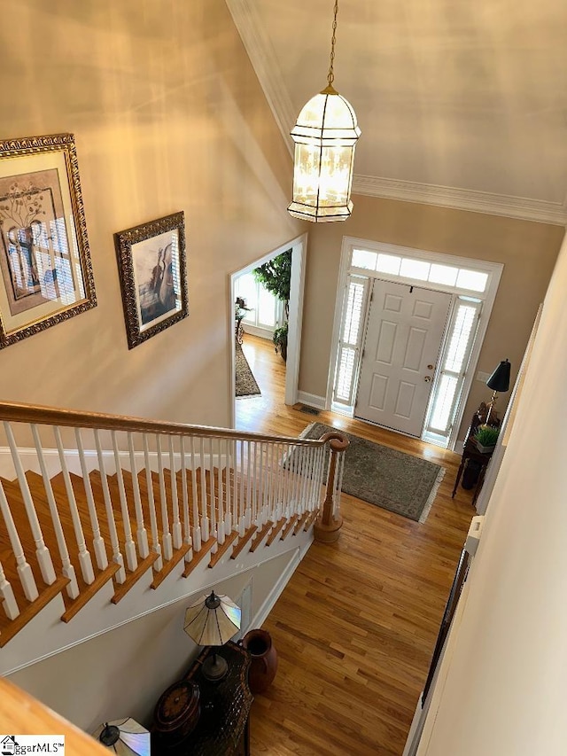 foyer featuring stairway, crown molding, and wood finished floors