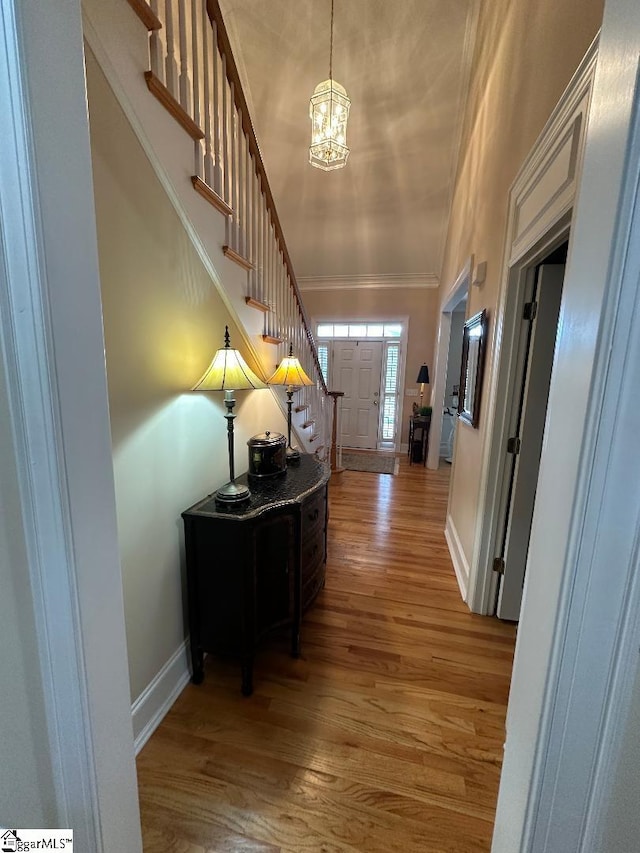 entryway with crown molding, baseboards, a chandelier, stairway, and wood finished floors