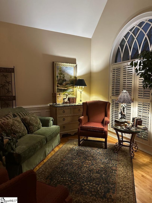 sitting room featuring a wainscoted wall, lofted ceiling, and wood finished floors