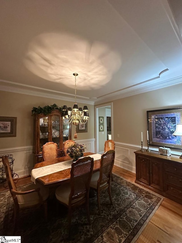 dining area with a chandelier, crown molding, and light wood finished floors