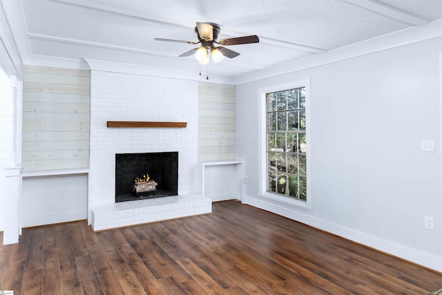 unfurnished living room featuring wood finished floors, baseboards, ceiling fan, a brick fireplace, and beamed ceiling