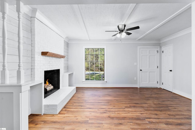 unfurnished living room with wood finished floors, a ceiling fan, baseboards, a fireplace, and ornamental molding