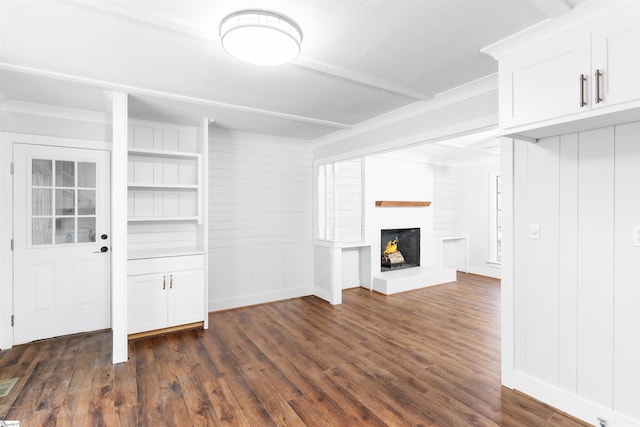 unfurnished living room with baseboards, a brick fireplace, and dark wood-style floors