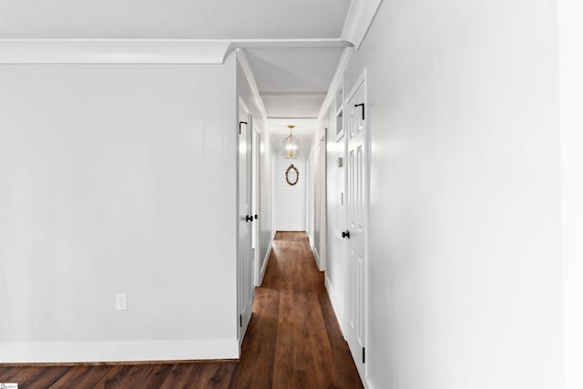 hall featuring dark wood-style floors, baseboards, and ornamental molding