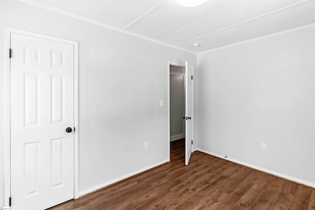 unfurnished bedroom featuring baseboards, wood finished floors, and ornamental molding