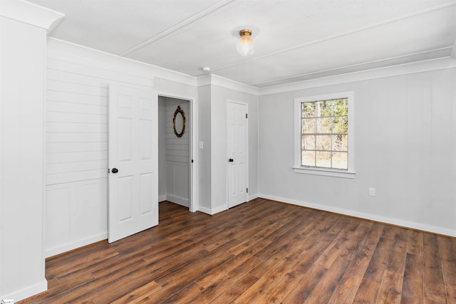 unfurnished bedroom featuring baseboards, dark wood-style flooring, and ornamental molding