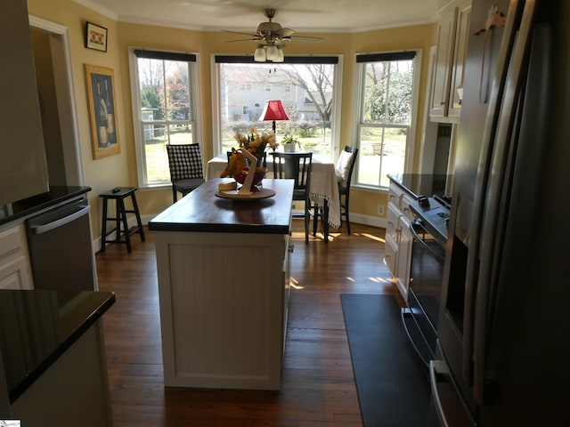 kitchen with white cabinetry, dark countertops, stainless steel refrigerator with ice dispenser, and crown molding