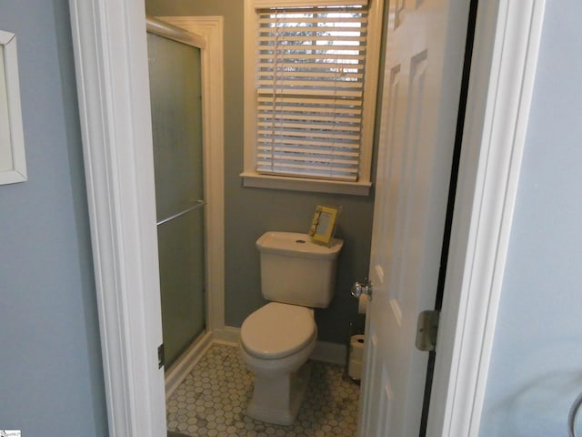 full bath featuring a shower stall, toilet, baseboards, and tile patterned floors