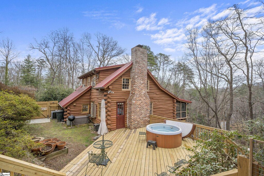 143 Caledonia Rd, Landrum, SC 29356 - exterior space featuring fence, a wooden deck, log siding, a chimney, and a hot tub