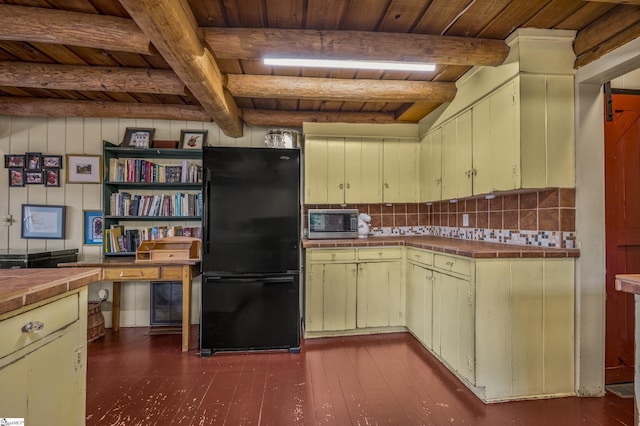 kitchen with dark wood-style floors, stainless steel microwave, tile countertops, and freestanding refrigerator