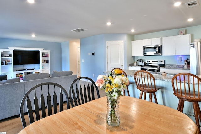 dining space with light wood finished floors, visible vents, and recessed lighting