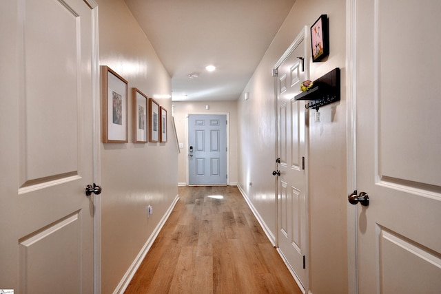 hall with baseboards and light wood finished floors