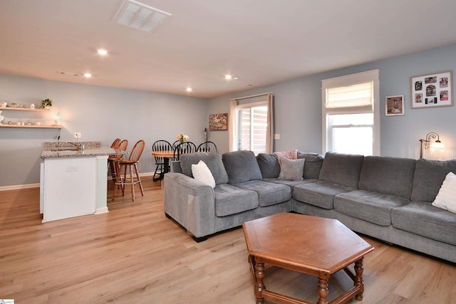 living area with recessed lighting, visible vents, baseboards, and light wood finished floors