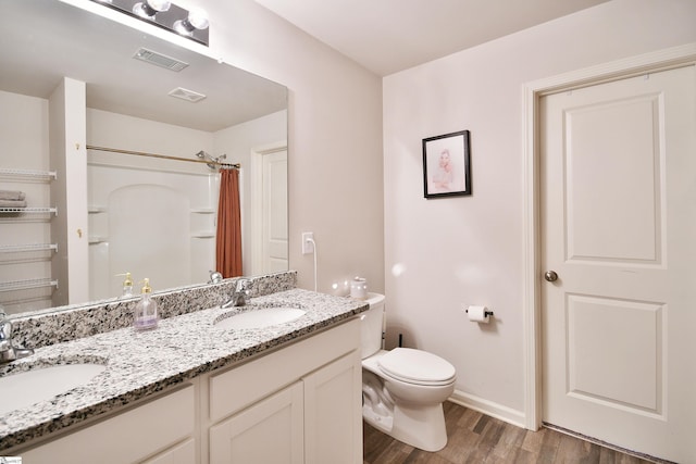 bathroom with visible vents, toilet, wood finished floors, and a sink