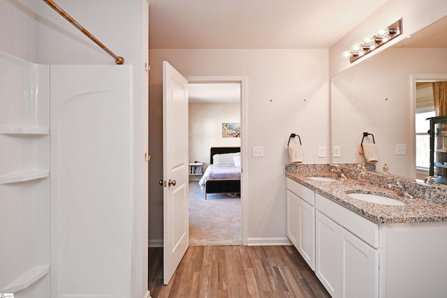 ensuite bathroom featuring ensuite bath, wood finished floors, double vanity, and a sink