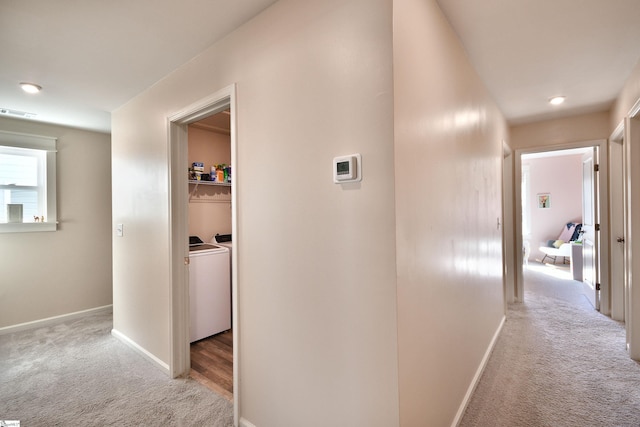 corridor featuring visible vents, washing machine and dryer, carpet, and baseboards