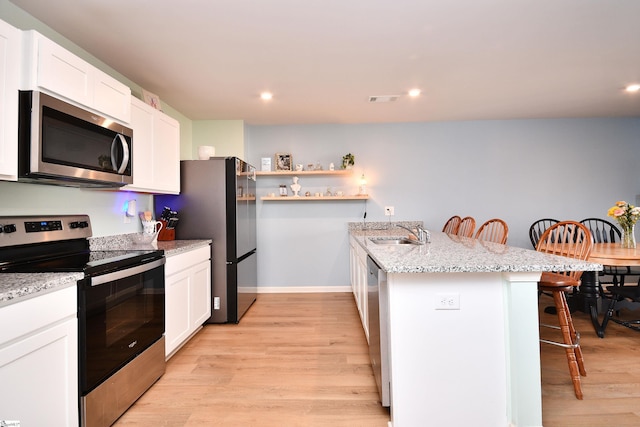 kitchen with visible vents, a peninsula, a sink, stainless steel appliances, and a kitchen bar