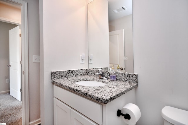 half bath with visible vents, toilet, vanity, and baseboards