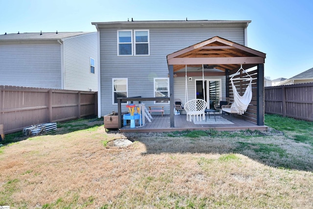 back of property featuring a deck, a yard, and a fenced backyard