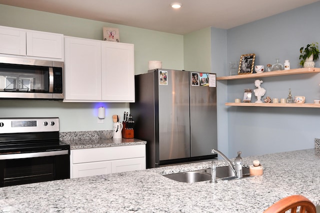 kitchen featuring light stone counters, open shelves, a sink, stainless steel appliances, and white cabinets