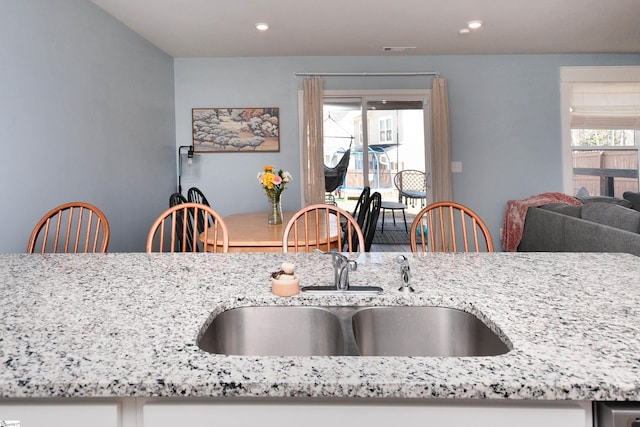 kitchen featuring a sink, visible vents, light stone countertops, and recessed lighting