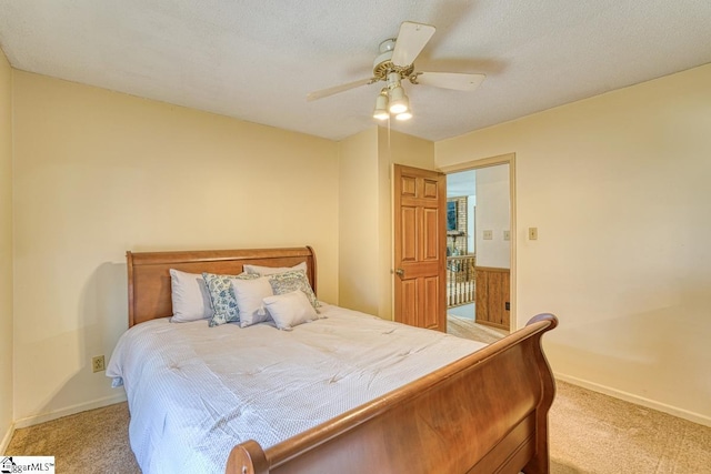 bedroom with baseboards, light carpet, a textured ceiling, and a ceiling fan