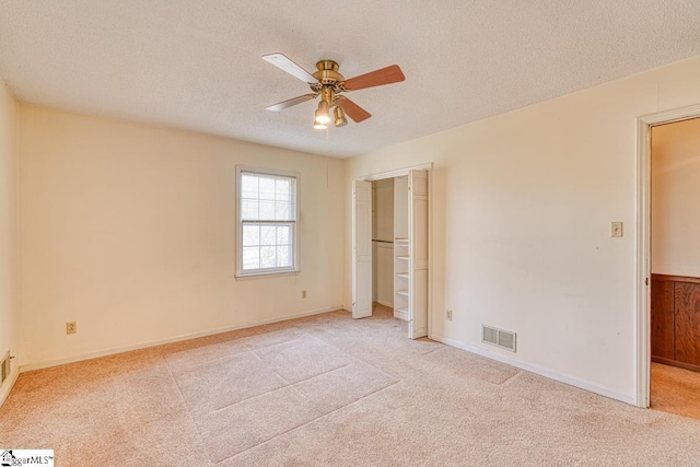 unfurnished bedroom featuring visible vents, light carpet, and a textured ceiling